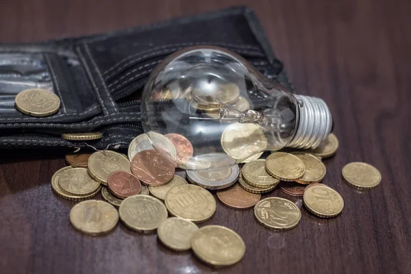 Light bulb near the wallet with money. Rise in electricity prices due to war in Ukraine