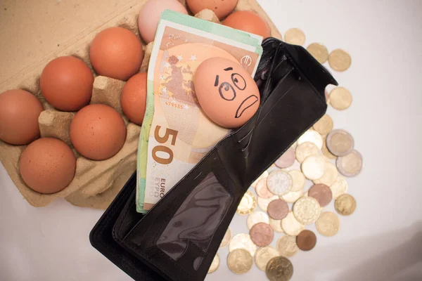 Frightened egg face on banknotes and coins. Rise in the price of eggs due to inflation.