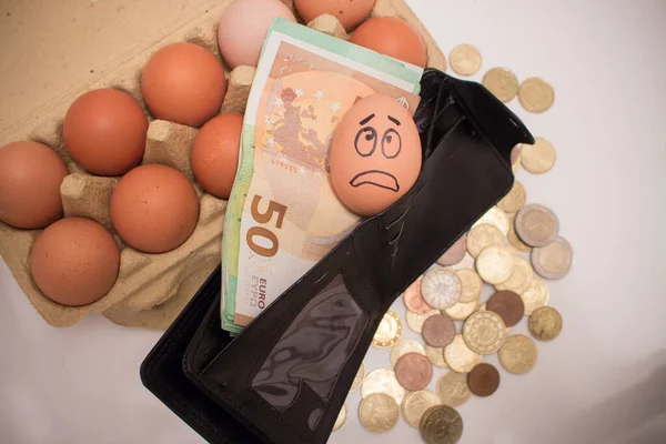 Frightened egg face on banknotes and coins. Rise in the price of eggs due to inflation.