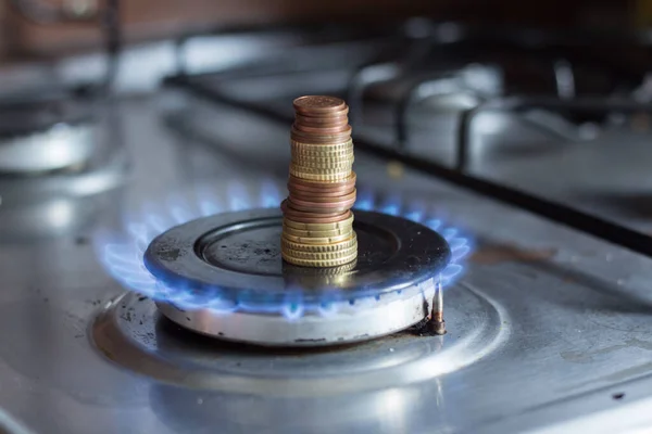 A column of coins on a gas stove. The rise in prices for utilities due to inflation and the war in Ukraine.