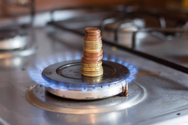 A column of coins on a gas stove. The rise in prices for utilities due to inflation and the war in Ukraine.