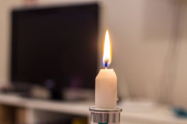 Burning candle on the background of the TV. Blackout due to war in Ukraine