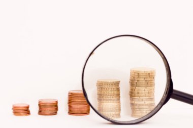 Columns of coins and a magnifying glass