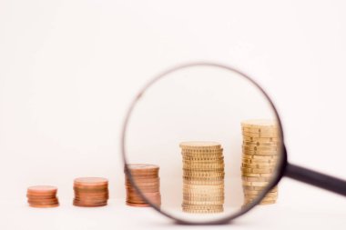 Columns of coins and a magnifying glass