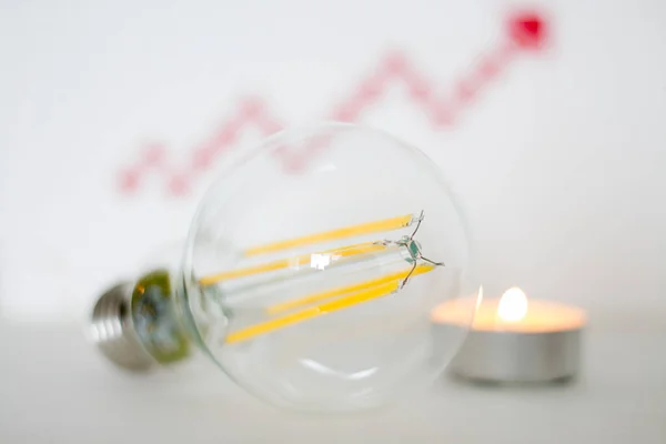 led light bulb with a candle on the background of a red growth arrow.