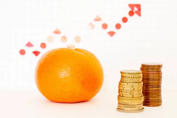 Stock image Mandarin with columns of coins against the background of a red growth arrow.