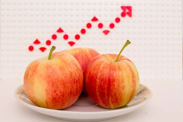 Apples on a saucer against the background of a growth chart.