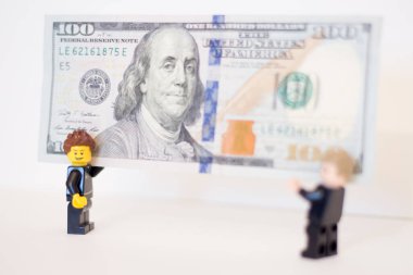 Oyuncak adamların elinde 100 dolarlık banknot var..