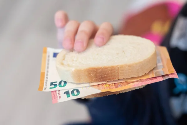 The child holds money on a piece of bread. World crisis. Rise in price of products.
