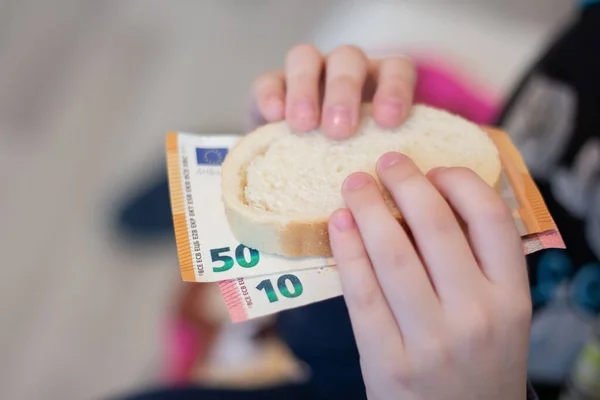The child holds money on a piece of bread. World crisis. Rise in price of products.