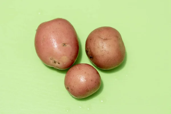 Três Batatas Uma Placa Verde — Fotografia de Stock