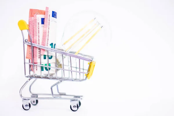 stock image Energy saving lamp in a shopping cart with euro banknotes. Rising electricity prices.