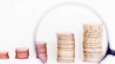 Columns of coins and a magnifying glass