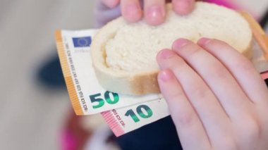 Çocuk bir parça ekmek üzerinde para tutuyor. Dünya krizi. Ürünlerin fiyatlarında artış