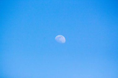 Mavi gökyüzünde gündüz vakti ay.