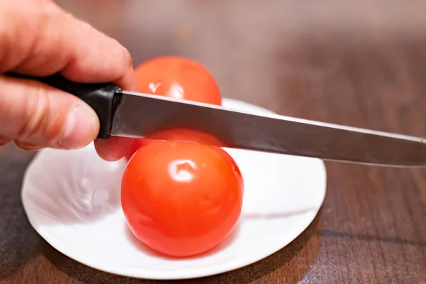 Slicing a tomato with a knife in hand close-up