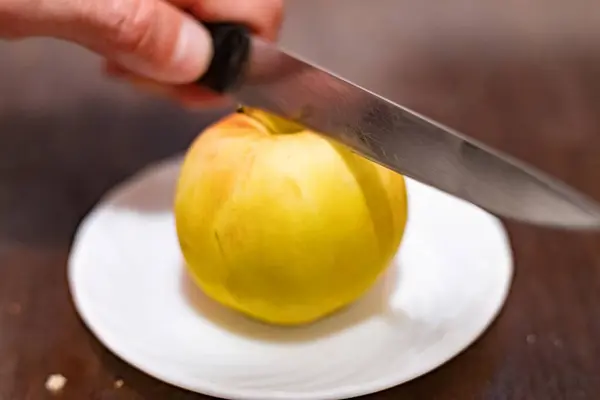 Slicing an apple with a knife in hand close-up