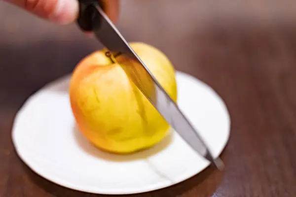 Slicing an apple with a knife in hand close-up