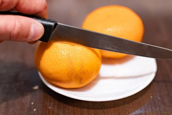 Slicing a tangerine with a knife in hand close-up