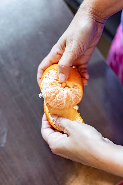 Peeling a tangerine with a woman's hands