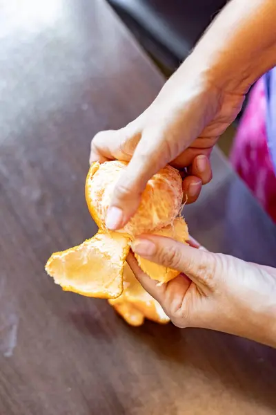 Peeling a tangerine with a woman\'s hands
