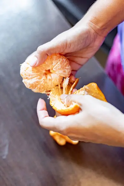 Peeling a tangerine with a woman's hands