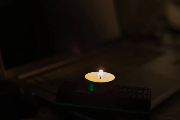 笔记本电脑键盘上的电话上燃着一支蜡烛 乌克兰战争造成的停电 — 图库照片