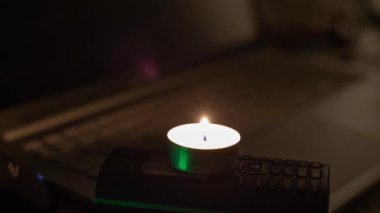  Yeni yıl ağacının arka planında yanan bir mum, bir telefon ve bir dizüstü bilgisayar. Ukrayna 'daki savaştan dolayı karartma