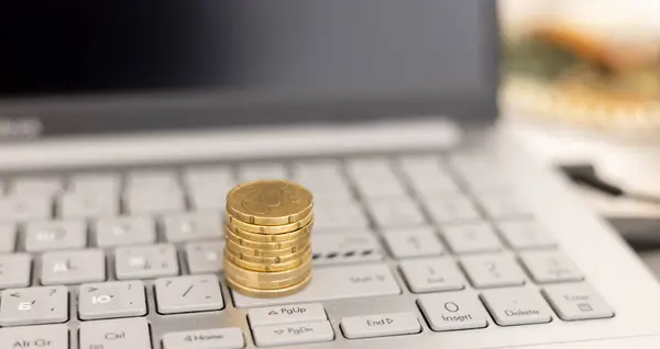 Euro coins on laptop keyboard close-up