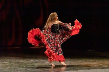 Ulusal elbiseli bir kız sahnede çingene dansı yapıyor.