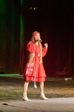 Ulusal Ukrayna kostümlü bir kız konserde sahneye çıkıyor.