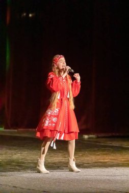 Ulusal Ukrayna kostümlü bir kız konserde sahneye çıkıyor.