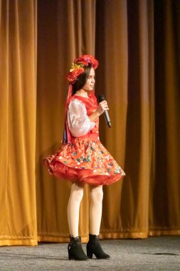 Ulusal Ukrayna kostümlü bir kız konserde sahneye çıkıyor.