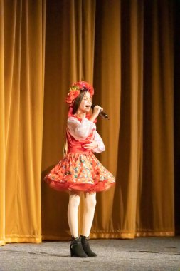 Ulusal Ukrayna kostümlü bir kız konserde sahneye çıkıyor.