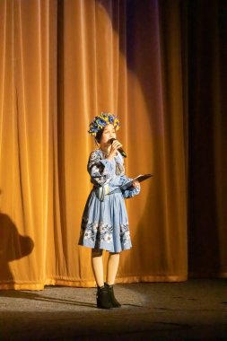 Ulusal Ukrayna kostümlü bir kız konserde sahneye çıkıyor.