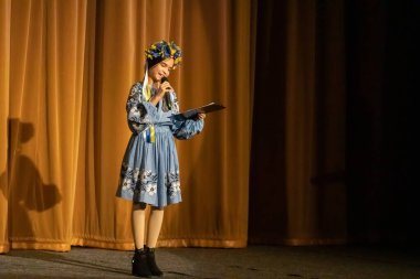 Ulusal Ukrayna kostümlü bir kız konserde sahneye çıkıyor.