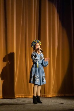 Ulusal Ukrayna kostümlü bir kız konserde sahneye çıkıyor.