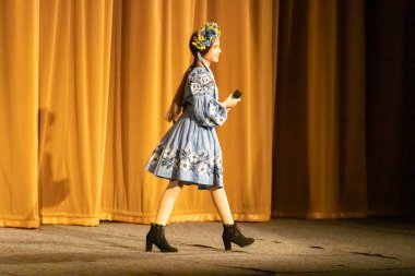 Ulusal Ukrayna kostümlü bir kız konserde sahneye çıkıyor.