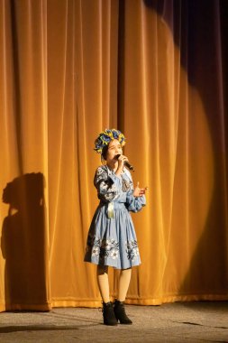 Ulusal Ukrayna kostümlü bir kız konserde sahneye çıkıyor.