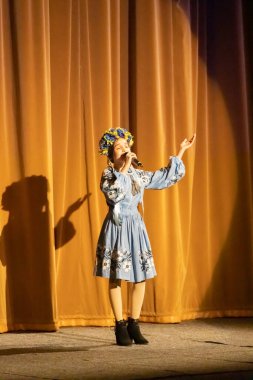 Ulusal Ukrayna kostümlü bir kız konserde sahneye çıkıyor.