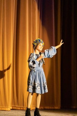 Ulusal Ukrayna kostümlü bir kız konserde sahneye çıkıyor.