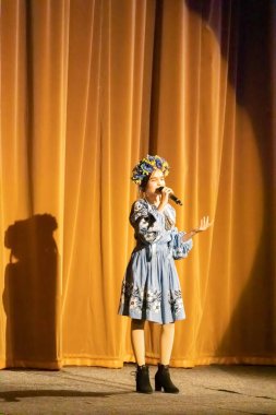 Ulusal Ukrayna kostümlü bir kız konserde sahneye çıkıyor.