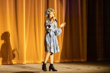 Ulusal Ukrayna kostümlü bir kız konserde sahneye çıkıyor.