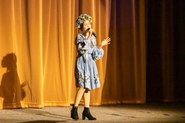 Ulusal Ukrayna kostümlü bir kız konserde sahneye çıkıyor.