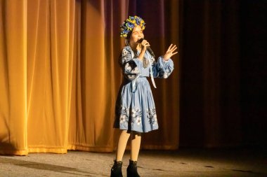 Ulusal Ukrayna kostümlü bir kız konserde sahneye çıkıyor.