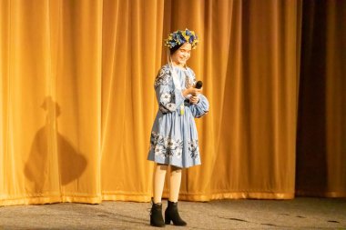 Ulusal Ukrayna kostümlü bir kız konserde sahneye çıkıyor.