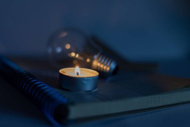 Çocuk defterinde mum ve lamba yakmak. Ukrayna 'daki savaştan dolayı elektrikle ilgili sorunlar