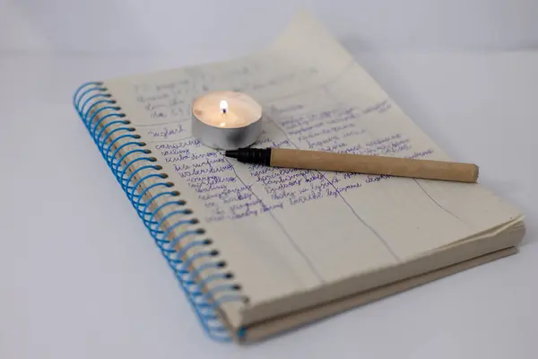 Burning candle on a children's notepad. Problems with electricity due to the war in Ukraine