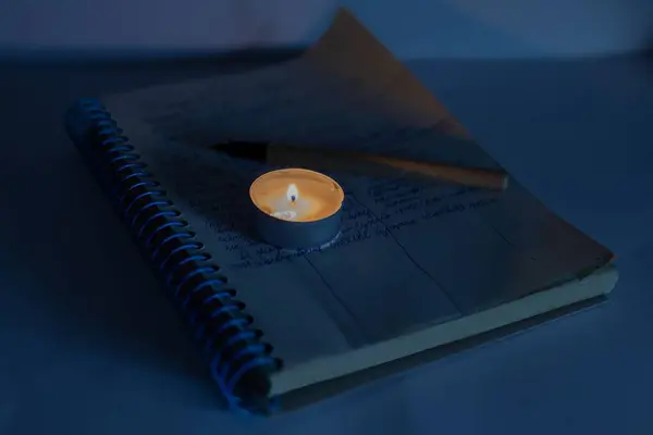 Burning candle on a children\'s notepad. Problems with electricity due to the war in Ukraine