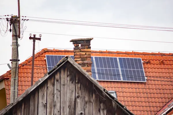 Solar battery on the roof of a house against the background of an old chimney and an old wooden roof